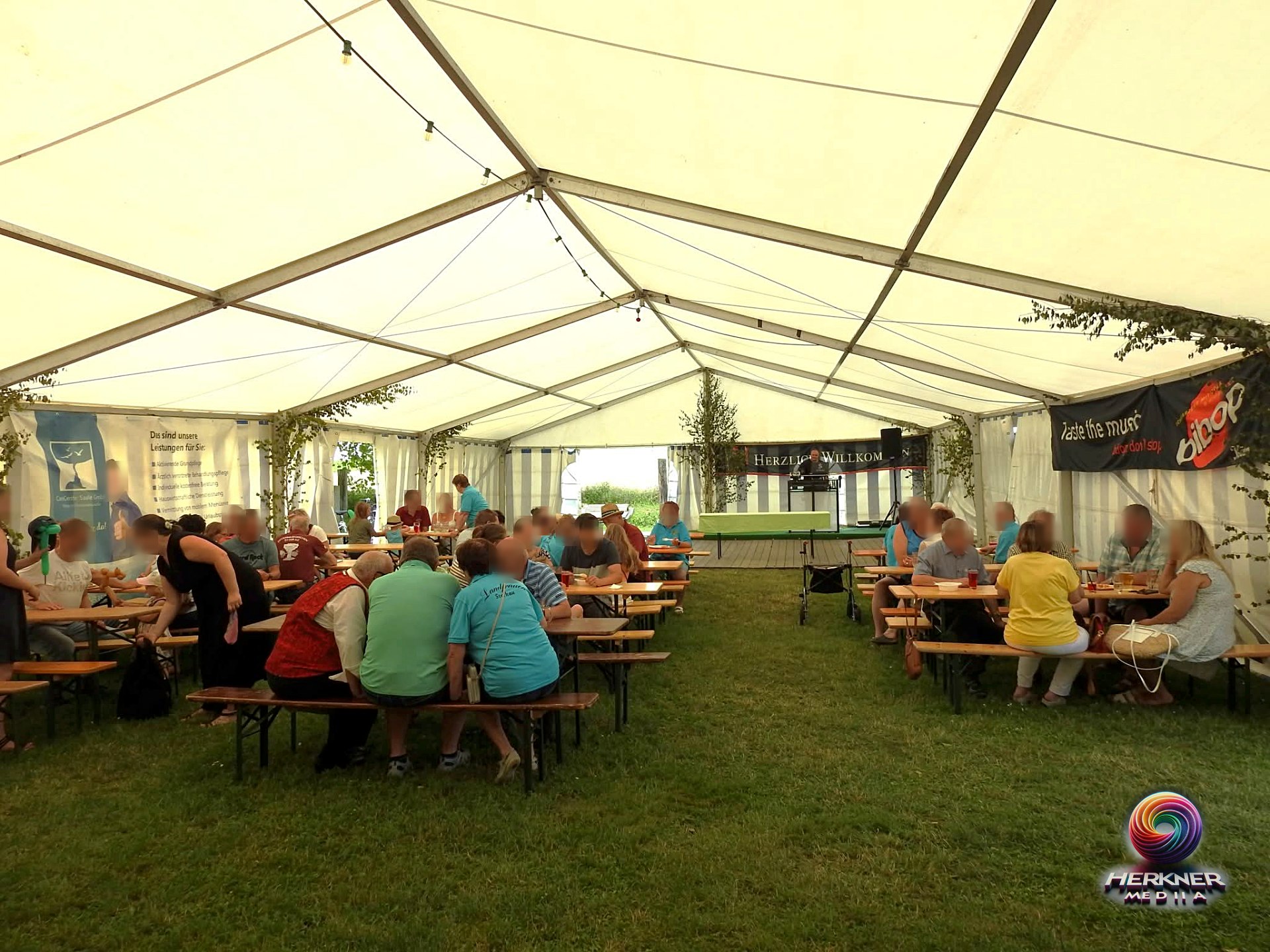 Festzelt-Panorama mit Gästen an Biertischgarnituren